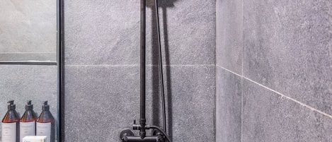 A modern shower with a handheld showerhead and a wall-mounted faucet.