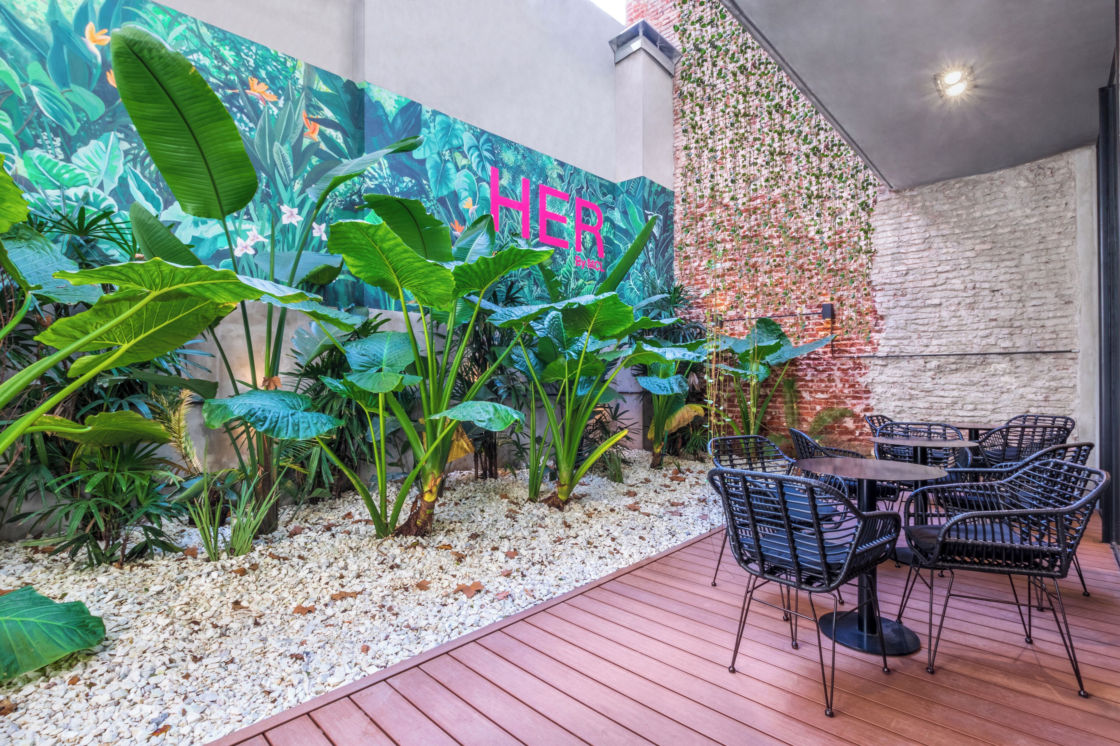 An outdoor patio with a mural, tropical plants, and a seating area.