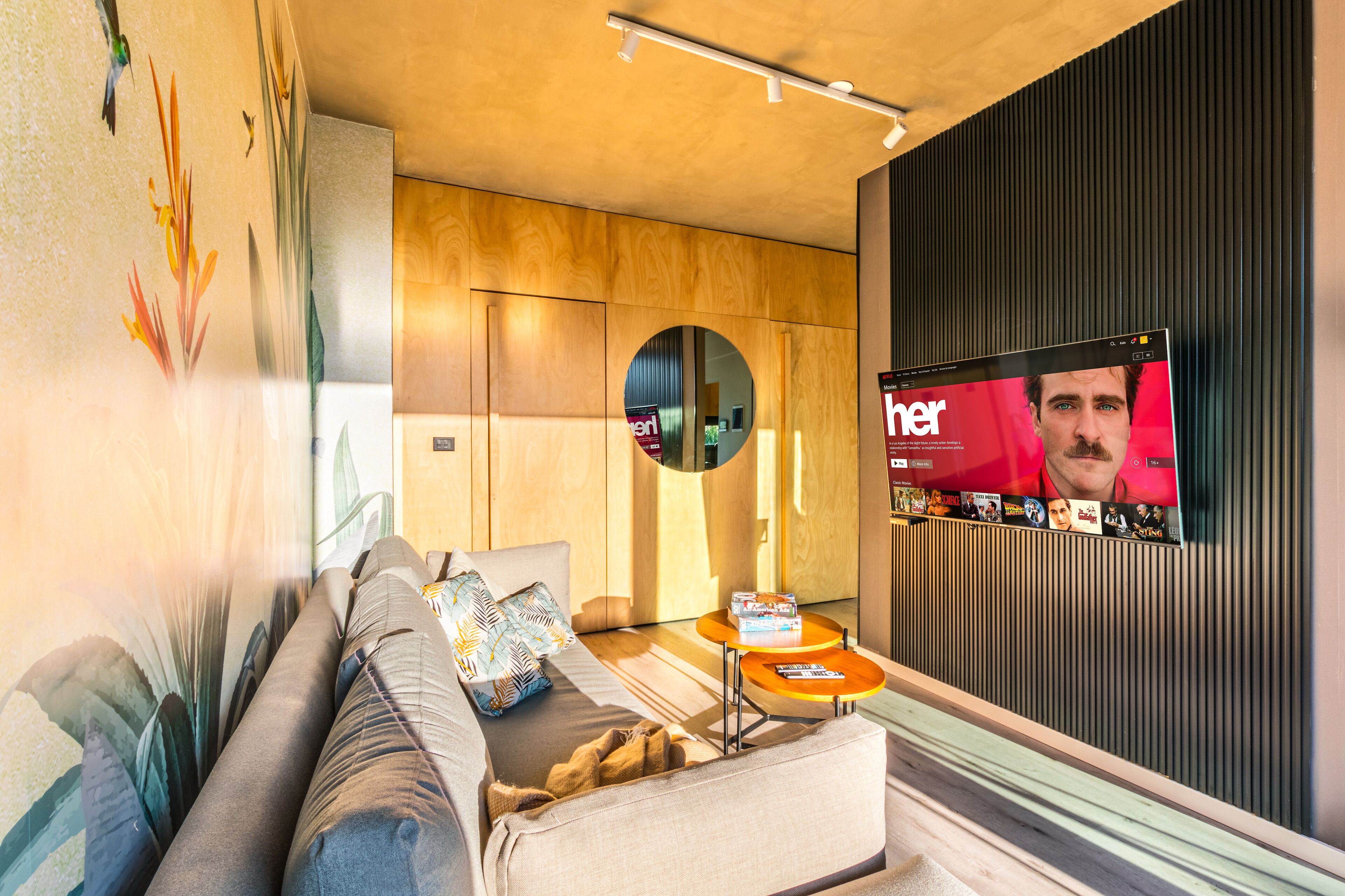 Un salón moderno con un sofá, una mesa de centro y un televisor mostrando la portada de una revista.