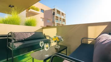 Ein Balkon mit einer Couch, einem kleinen Tisch und zwei Gläsern Wasser.