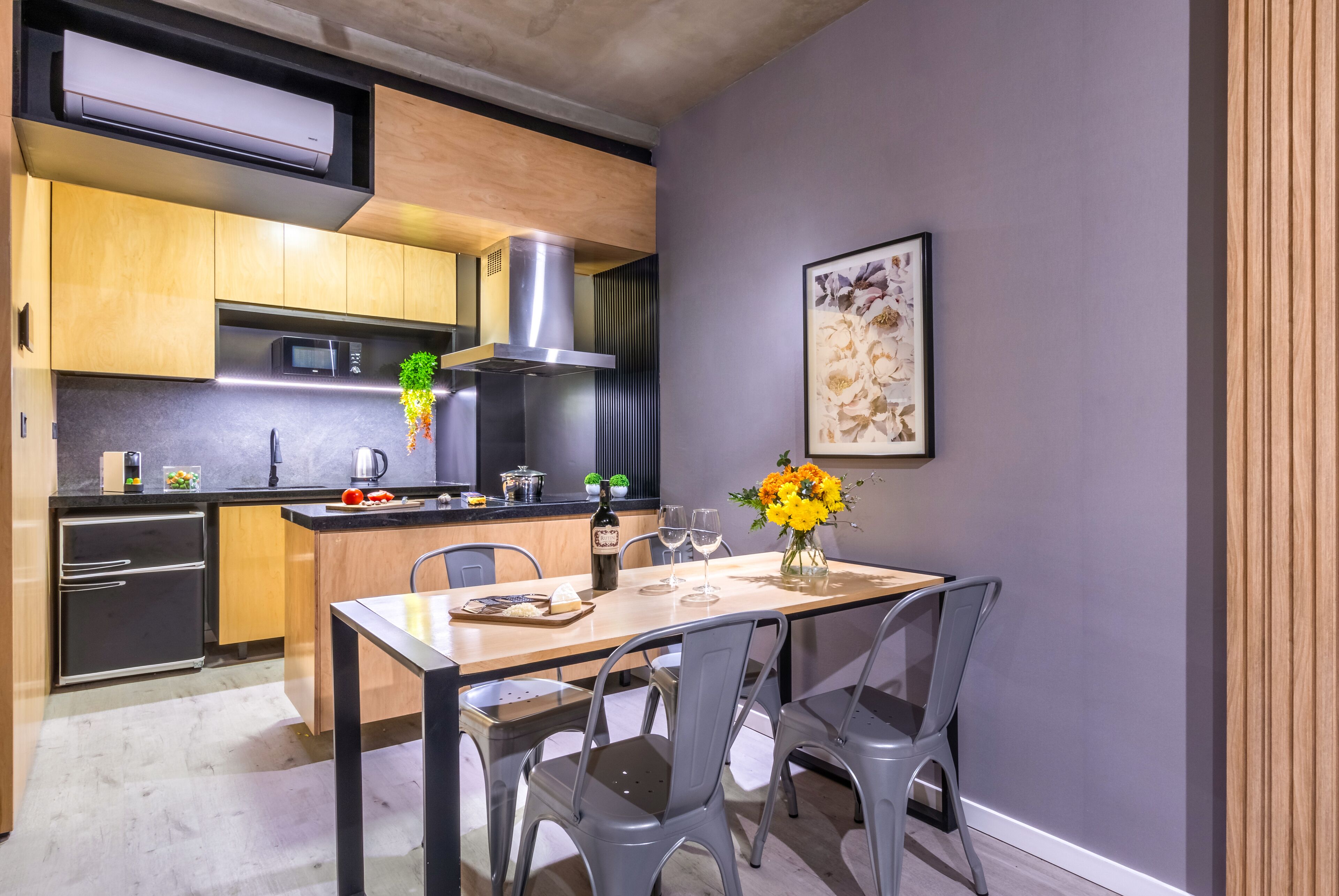 A modern kitchen with wooden cabinets, a stainless steel range hood, and a dining area with a table and chairs.