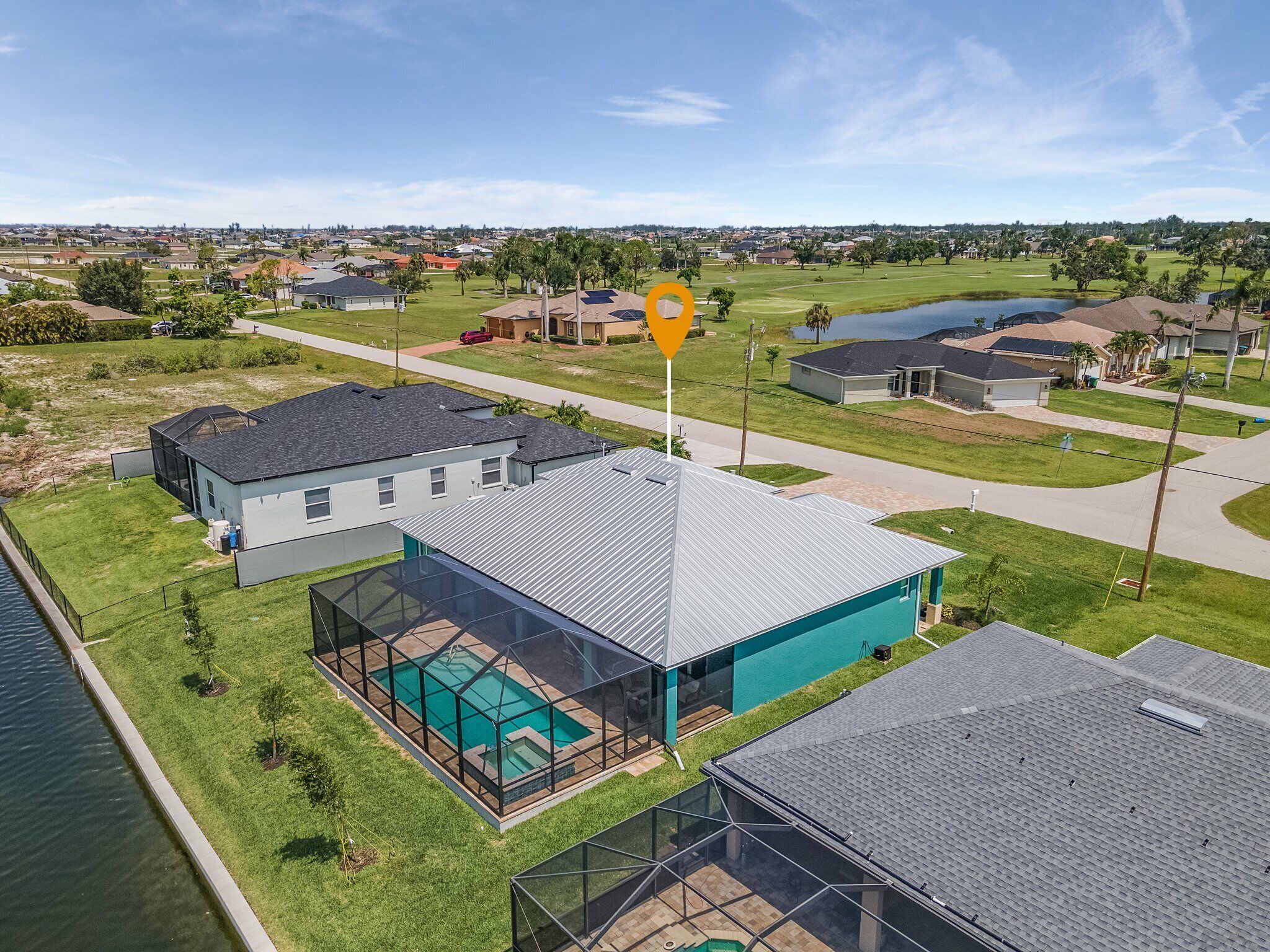 A residential area with houses, a swimming pool, and a golf course in the background.