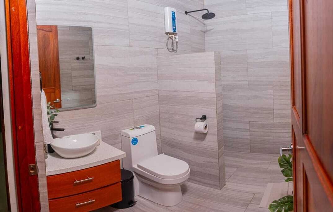 Une salle de bain moderne avec un lavabo, des toilettes et une douche, le tout de couleur blanche.