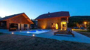 Une cabane en bois à deux étages, dotée d’une piscine, d’un espace extérieur aménagé et d’une entrée bien éclairée.