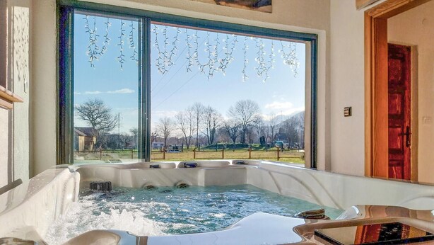 Un bain à remous avec vue sur un paysage rural, visible à travers une grande fenêtre.
