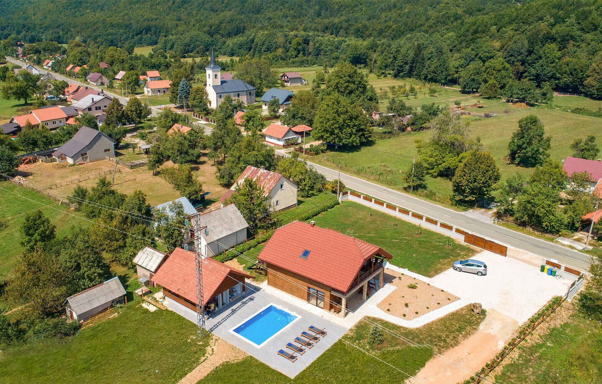 An aerial view of a residential area with houses, a church, and a swimming pool.