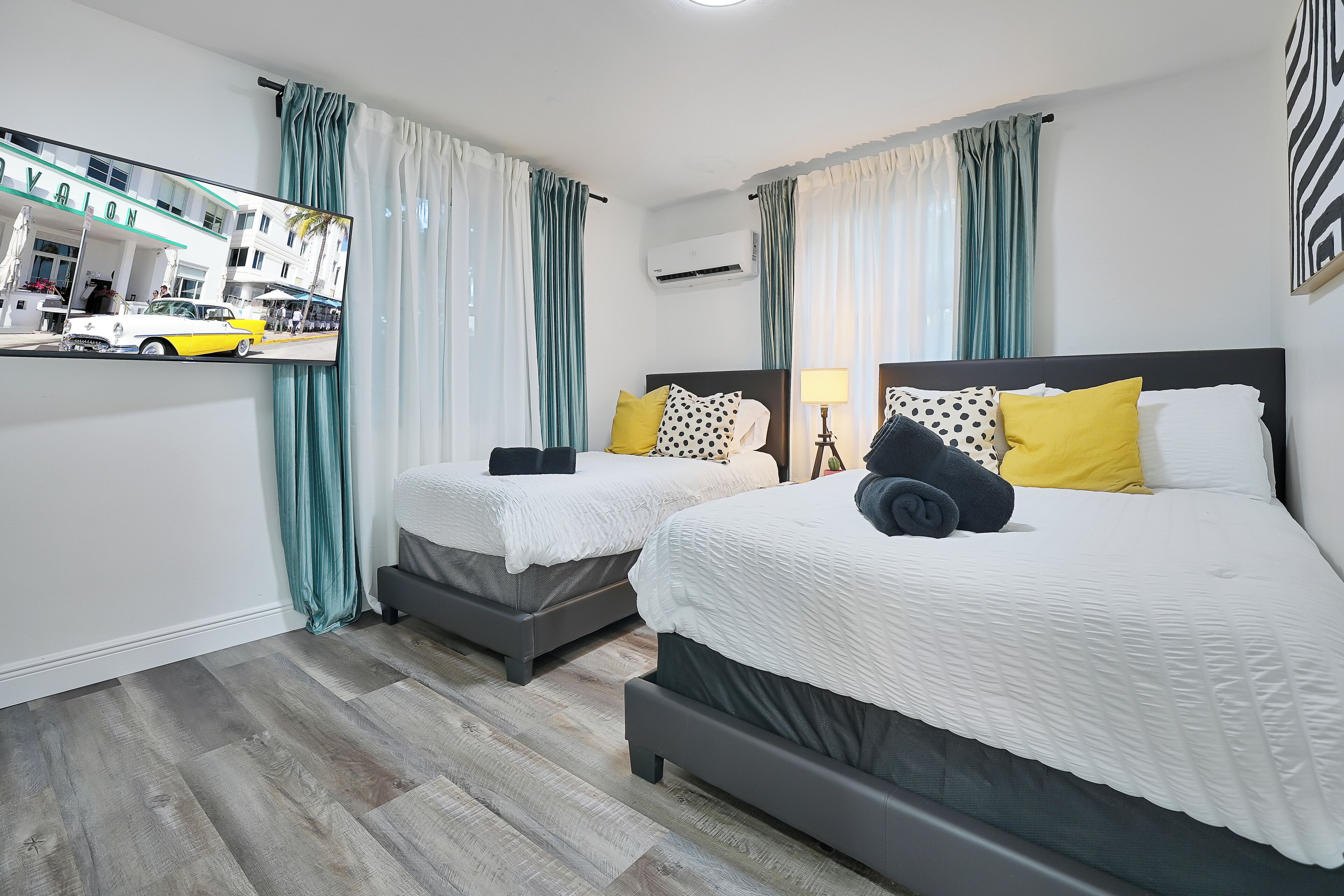 Quarto de hotel com duas camas, um espelho e vista para a rua.