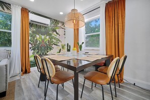 A dining area with a table, chairs, and a hanging light fixture. - 4 to 14 Guests, 2 Kitchens, Jungle Retreat BBQ Patio (Miami)