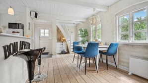 A modern kitchen with white cabinetry, a wooden floor, and a dining area with blue chairs.