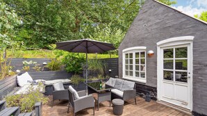 An outdoor patio with wicker furniture, a table, and an umbrella.