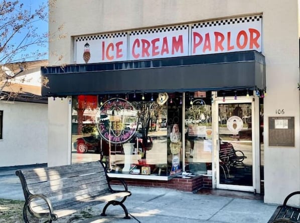 The exterior of an ice cream parlor with a storefront sign, a bench outside, and a number '106' on the building.