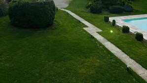 Un jardín bien cuidado con una piscina, setos ordenados y un sendero sinuoso.