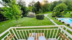 Una terraza de madera con una mesa y sillas, rodeada por una barandilla blanca.