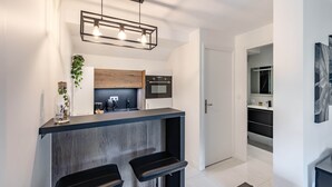 Una cocina moderna con barra, armarios de madera y una lámpara colgante.