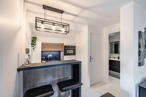 A modern kitchen with a bar area, wooden cabinets, and a hanging light fixture.