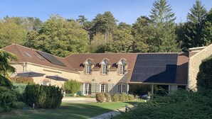 Una casa de piedra con techo inclinado, paneles solares y un porche cubierto.