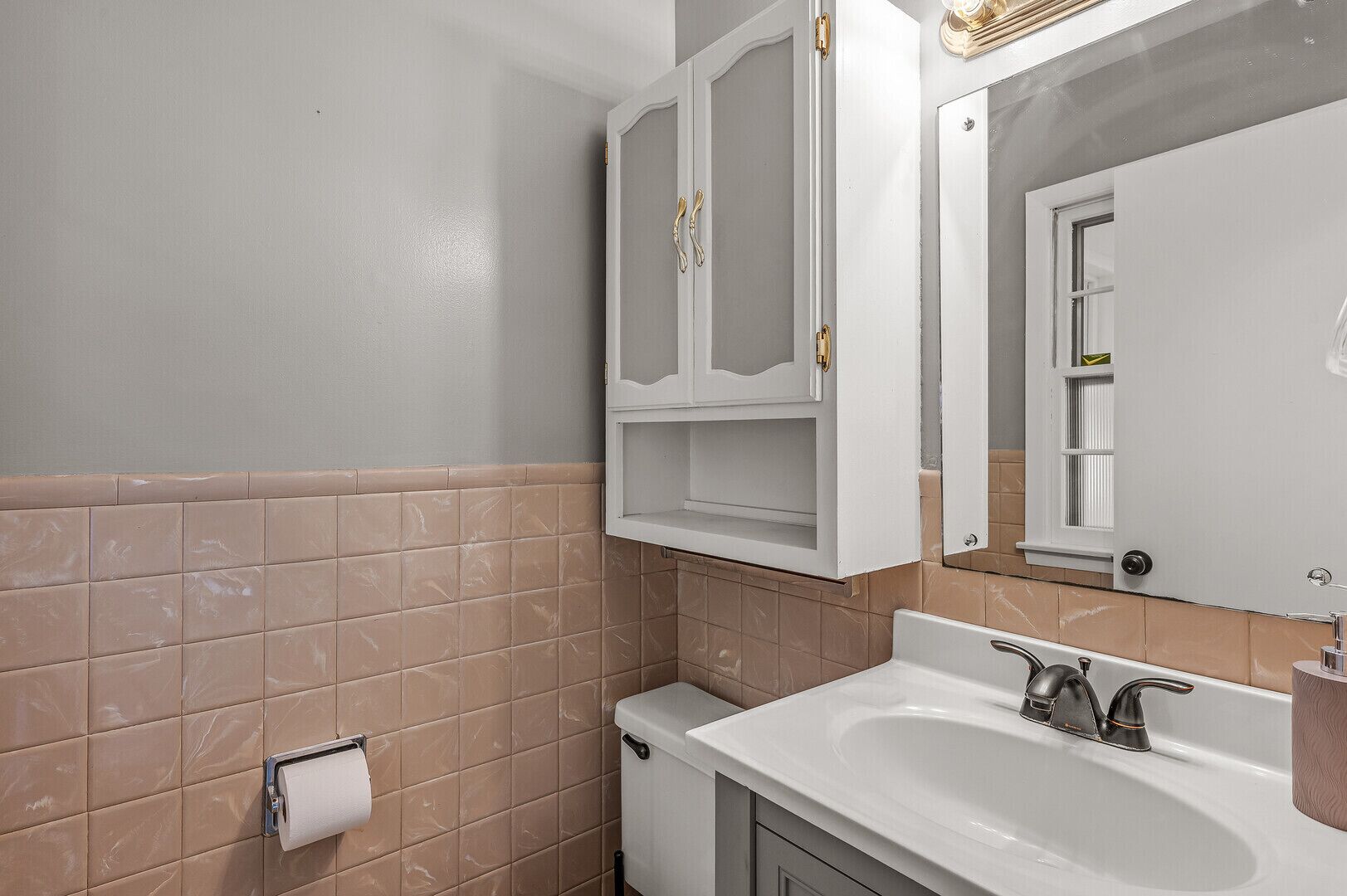 Une salle de bain avec un lavabo blanc, un miroir et des toilettes.