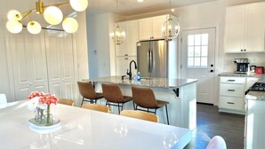 Una cocina moderna con armarios blancos, un refrigerador de acero inoxidable y una isla central con asientos.