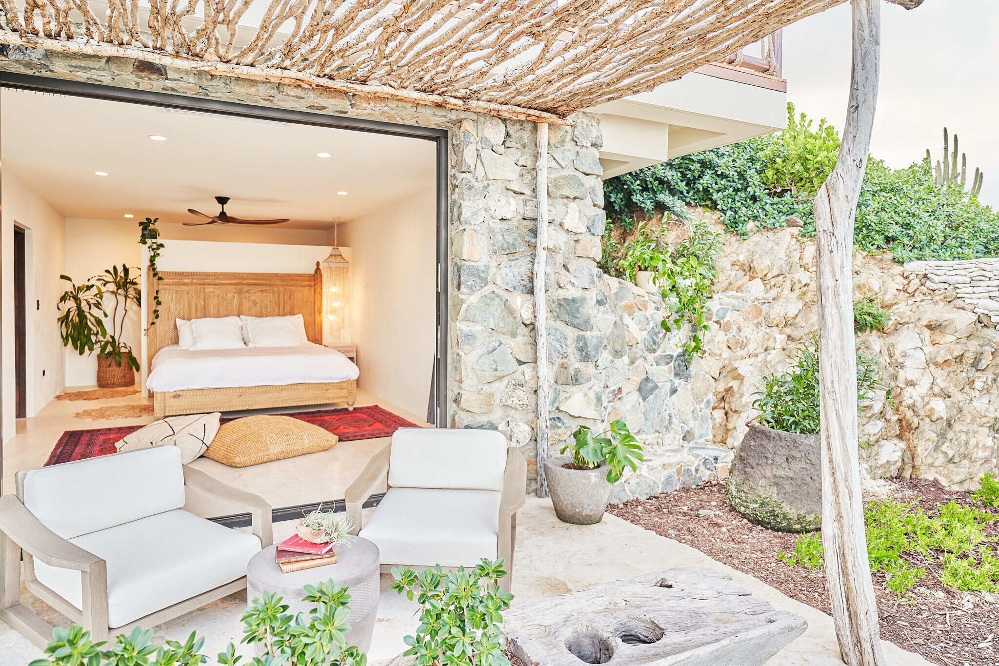 A bedroom with a bed, a ceiling fan, and a view of the garden.