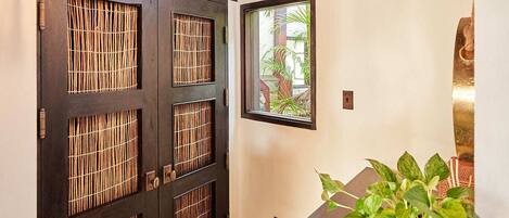 A hallway with a dark wooden door, a large chandelier, a small window, and a potted plant.