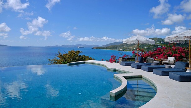 A infinity pool with a view of the sea and mountains, outdoor seating with umbrellas, and a clear blue sky. - The Aerial, BVI (East End)