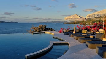 Una piscina al aire libre, sombrillas, sillones reclinables de piscina