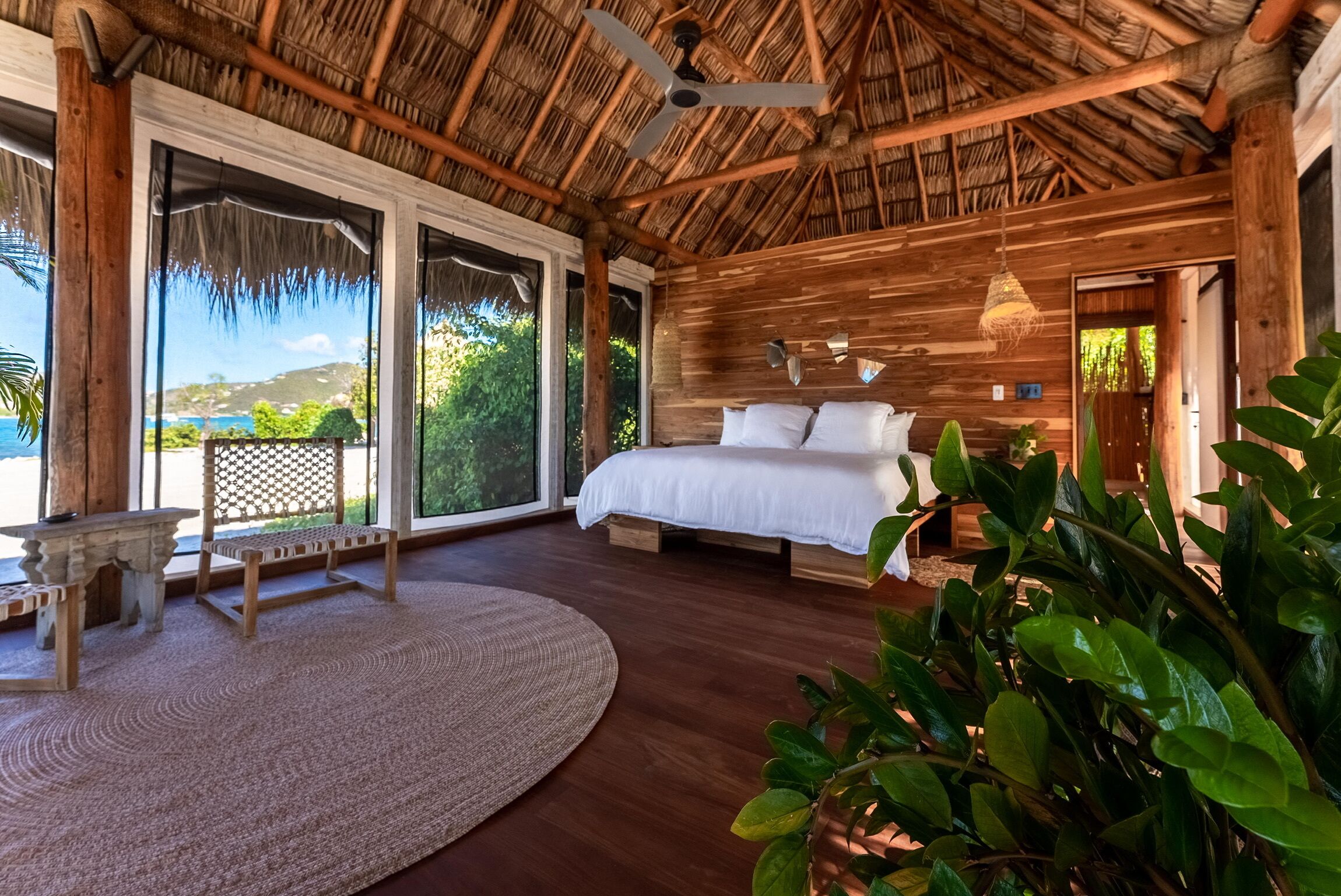 A spacious bedroom with a large bed, wooden walls, and a thatched roof.