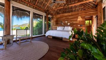 A spacious bedroom with a large bed, wooden walls, and a thatched roof.