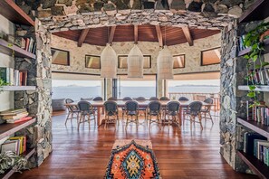 A dining area with a stone arch, wooden ceiling, and a view of the sea.