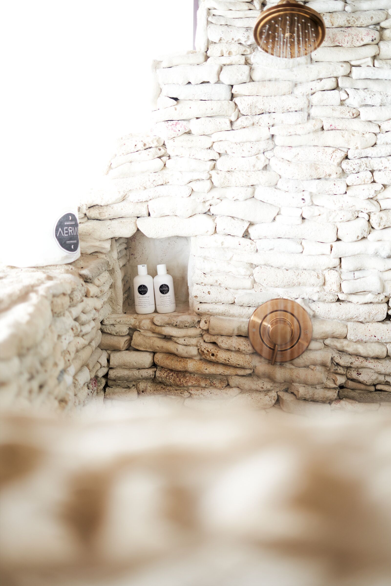 A stone wall with two bottles of lotion and a metal door handle.