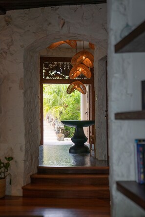 A stone archway leading to a garden with a water feature and hanging lights.
