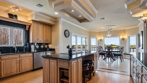 Una cocina amplia con armarios de madera, una isla central y un comedor con vistas.
