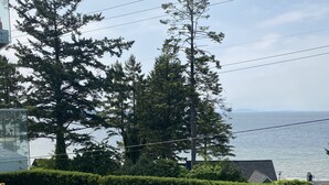 A residential property with a well-maintained lawn, a hedge, and a view of the sea. - White Rock Beach Getaway (White Rock)