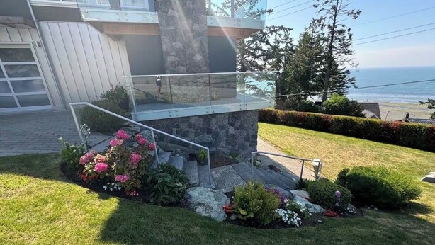 A modern house with a stone staircase, a glass balcony, and a well-maintained garden. - White Rock Beach Getaway (White Rock)