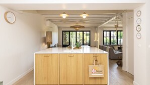 A modern kitchen with a central island, wooden cabinets, and pendant lighting.