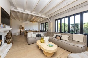 Uma sala de estar ampla com uma janela grande, lareira e um espaço de estar aconchegante.