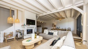 A spacious living room with a fireplace, a sofa, a coffee table, and a dining area.