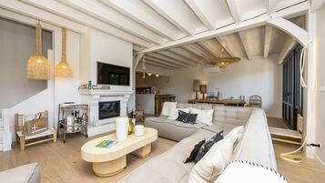 Ein geräumiges Wohnzimmer mit Kamin, einer Couch, einem Couchtisch und einem Essbereich.