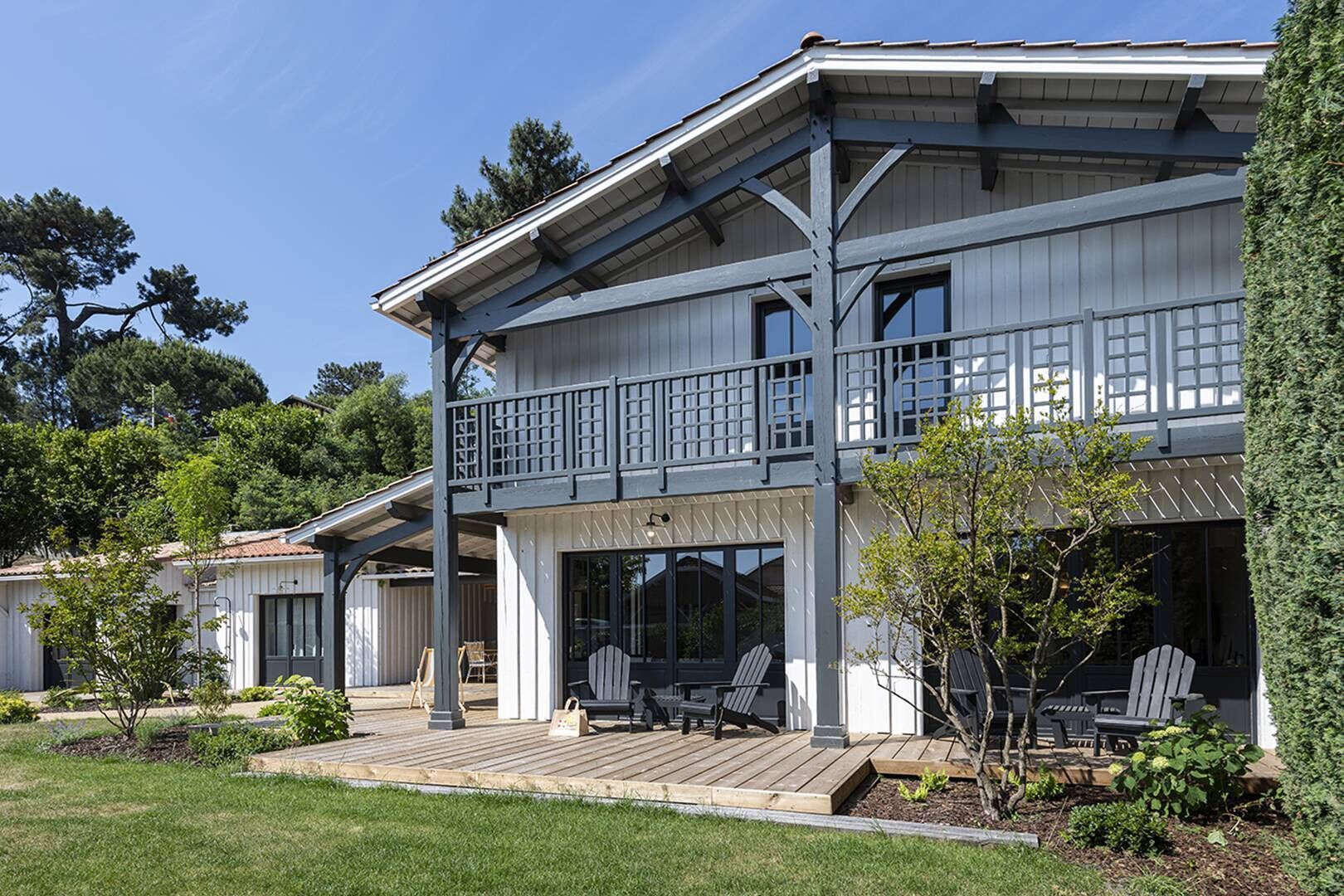 A two-story building with a balcony, outdoor seating, and a well-maintained garden.