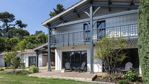 A two-story building with a balcony, outdoor seating, and a well-maintained garden.