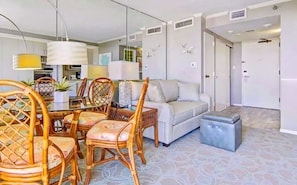 A modern living room with a dining area, a sofa, and a small table. - The San Luis Sunrise (Galveston)