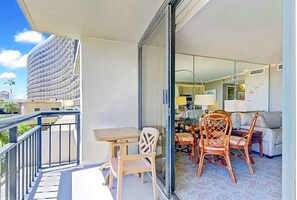 Enjoy a meal on the balcony with a view of the cityscape from the dining area, featuring a table, chairs, and sofa.