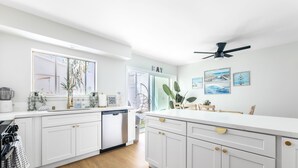 Una cocina moderna con armarios blancos, lavavajillas y ventilador de techo.