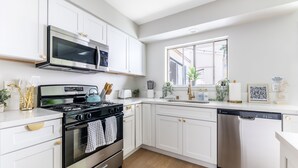 Una cocina moderna con armarios blancos, electrodomésticos de acero inoxidable y lavavajillas.