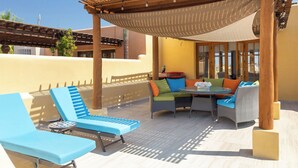 A covered outdoor seating area with lounge chairs and a table, surrounded by wooden pillars and a pergola. - BeautifulHome, in front of the community pool By Casago (Loreto)