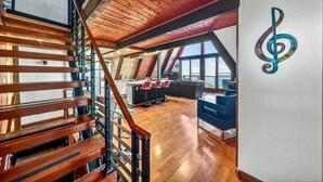 Een ruime loft met een houten trap, een eethoek en een groot raam met uitzicht.