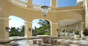 A spacious lobby with a checkered floor, multiple arches, and a central fountain.
