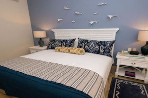 A hotel room with a bed, nightstands, a lamp, a wall with decorative elements, and a rug.