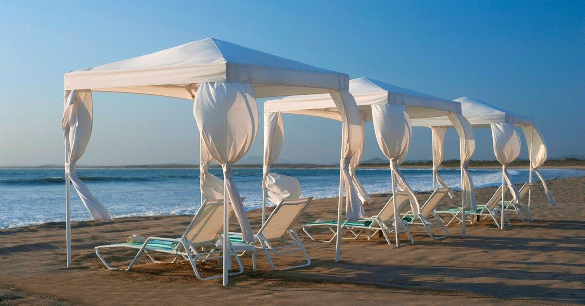 A beach with white canopies and lounge chairs.