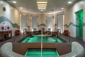 A spa area with a central pool, lounge chairs, and a reception desk.
